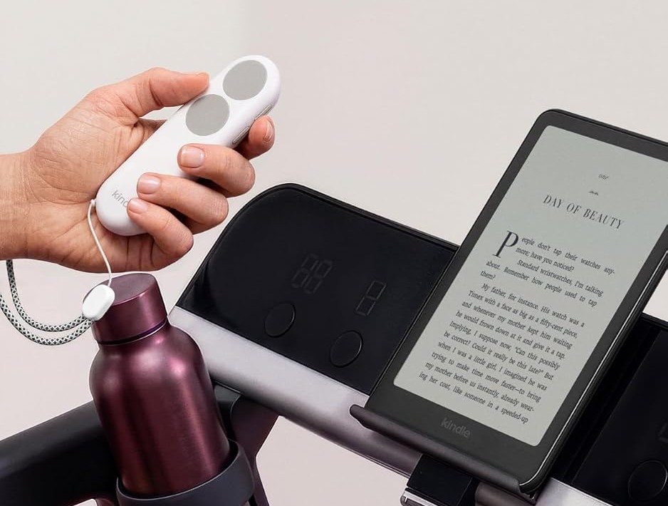 Kindle Paperwhite 2026 di dudukan treadmill dengan remote ganti halaman di tangan